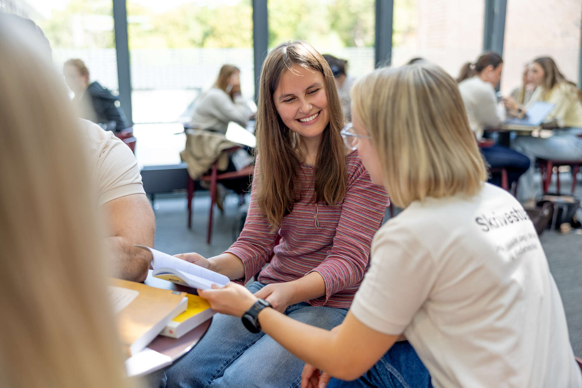 Skrivestua-veileder ser i bok sammen med student