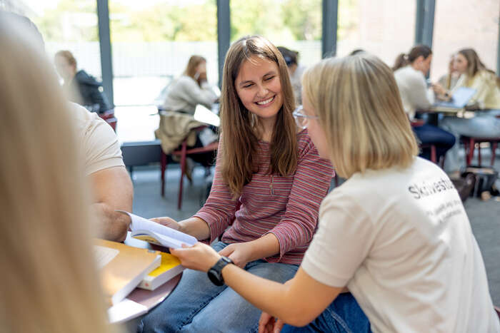 Skrivestua-veileder ser i bok sammen med student