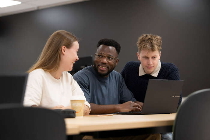Three students talking in front of a computer
