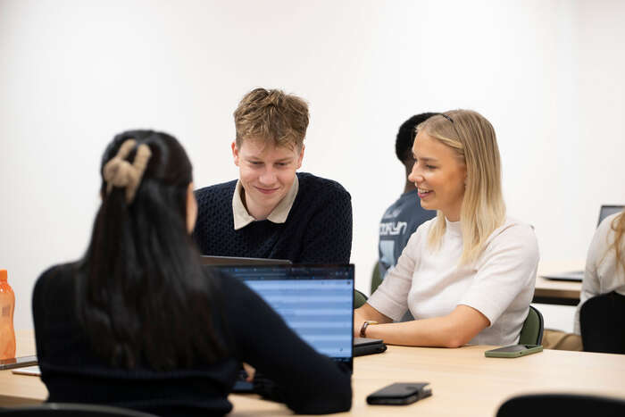 Bilde av tre studenter som sitter ved PCer