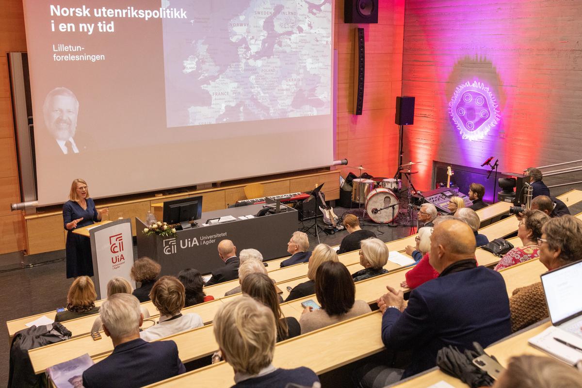 Bilde av taler i sal og publikum som lytter.