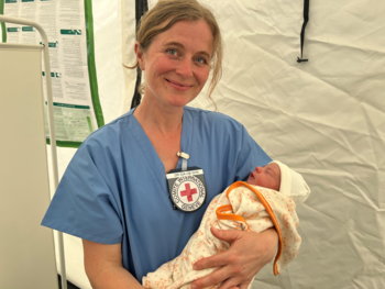 picture of Ida, in her scrubs, holding a baby 