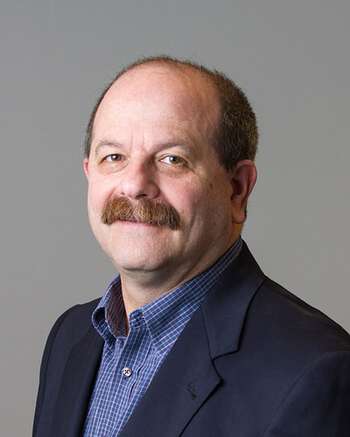 profile picture of man with blue suit, blue shirt and a brown mustache