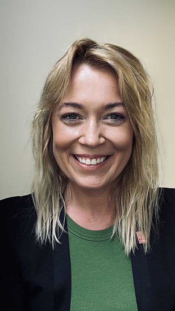 PhD candidate profile picture, smiling, clothed in green and black