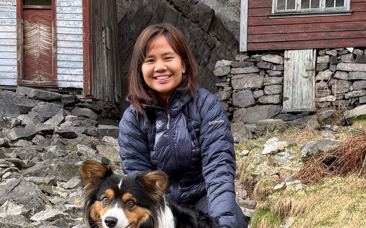Edlynne is sitting in nature and smiling at the camera