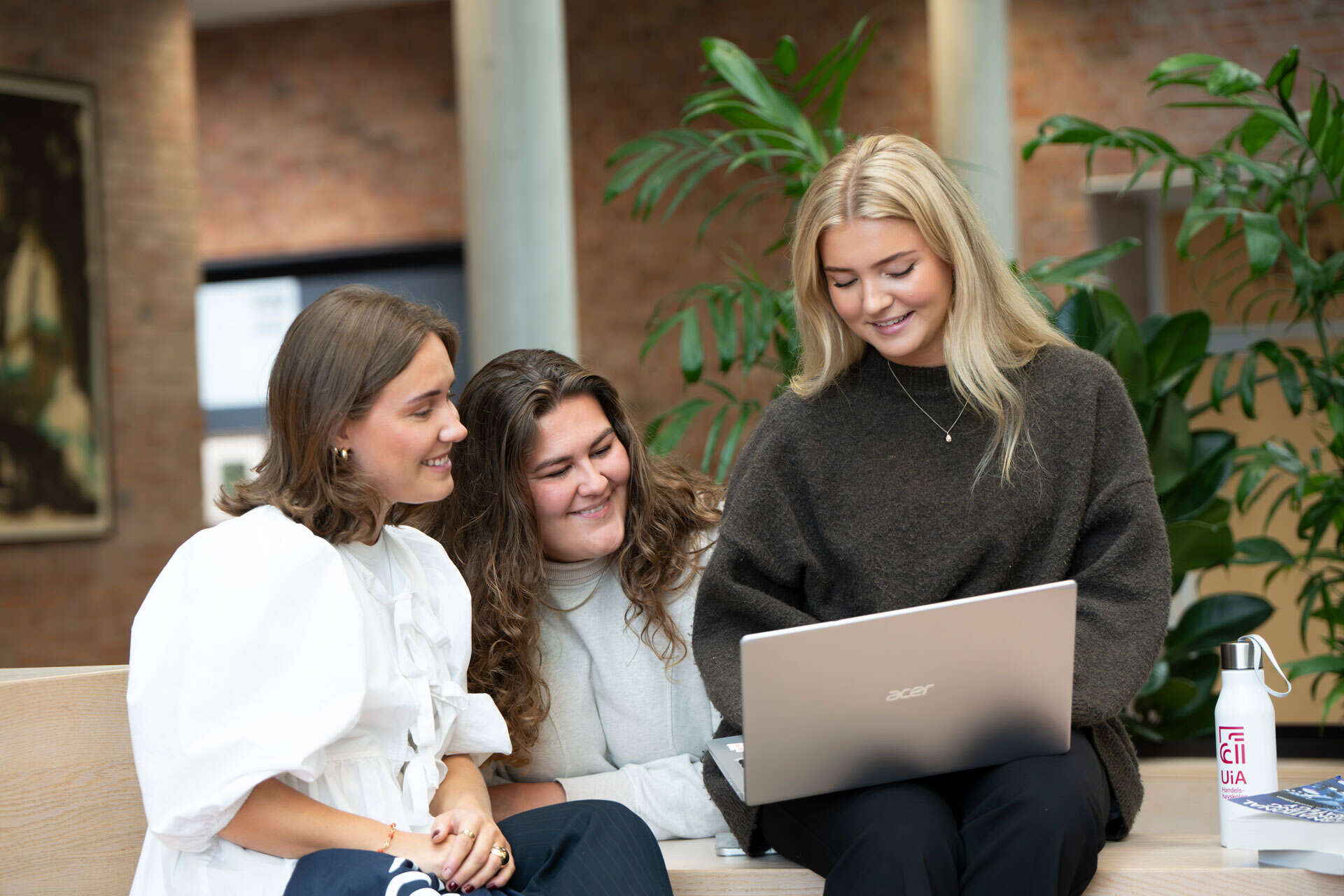 Bilde av tre studenter som ser på en PC sammen