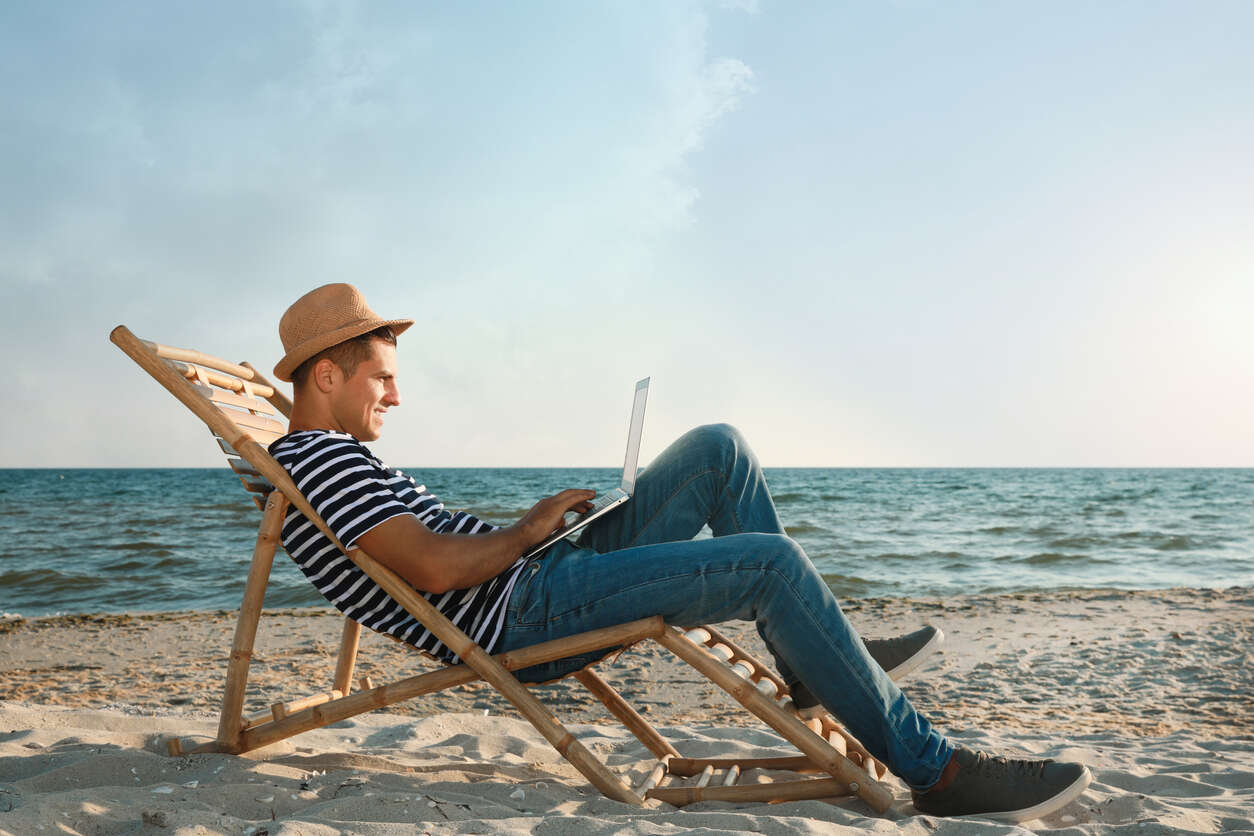 Mann på stranden med datamaskin