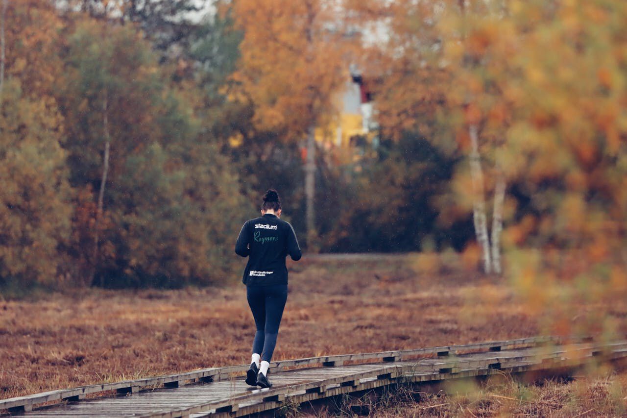 Bildet viser en kvinne som jogger ute i naturen.