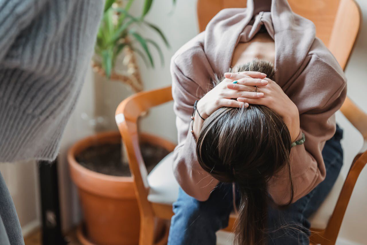 Bildet viser en tenåring som sitter oppgitt med hodet i fanget sitt på en stol.