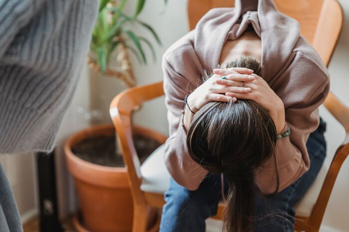 Bildet viser en tenåring som sitter oppgitt med hodet i fanget sitt på en stol.