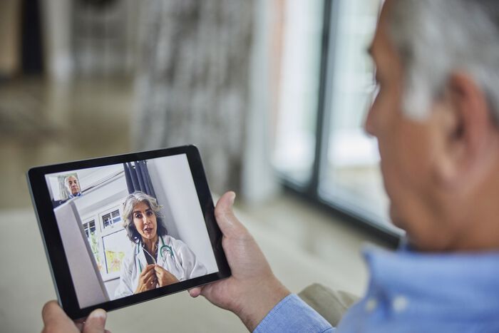 Mann konsulterer med legen via nettbrett