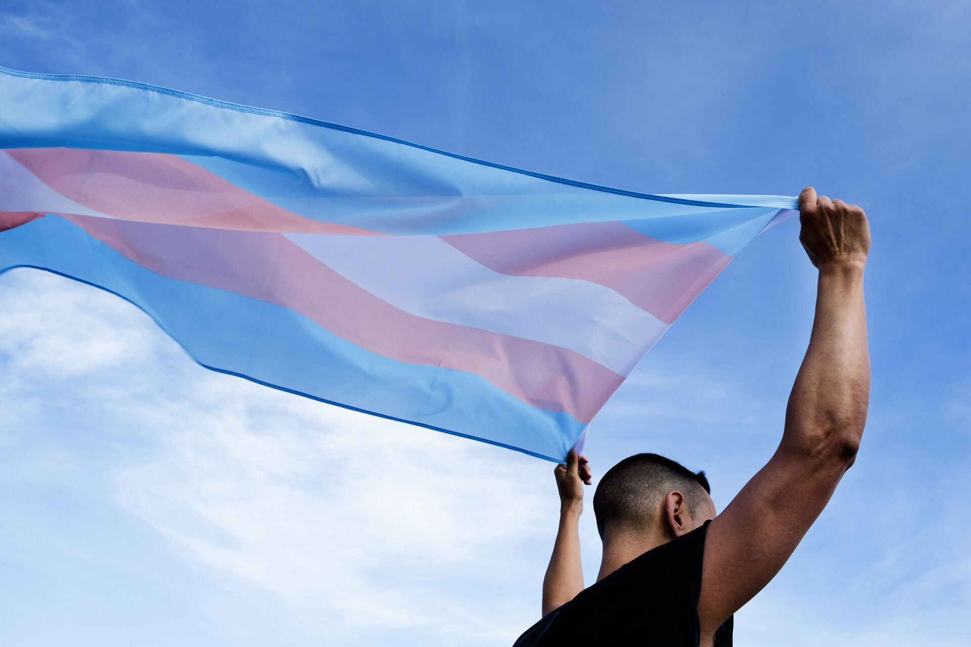 Photo of a person holding the flag with the colours blue, white and pink