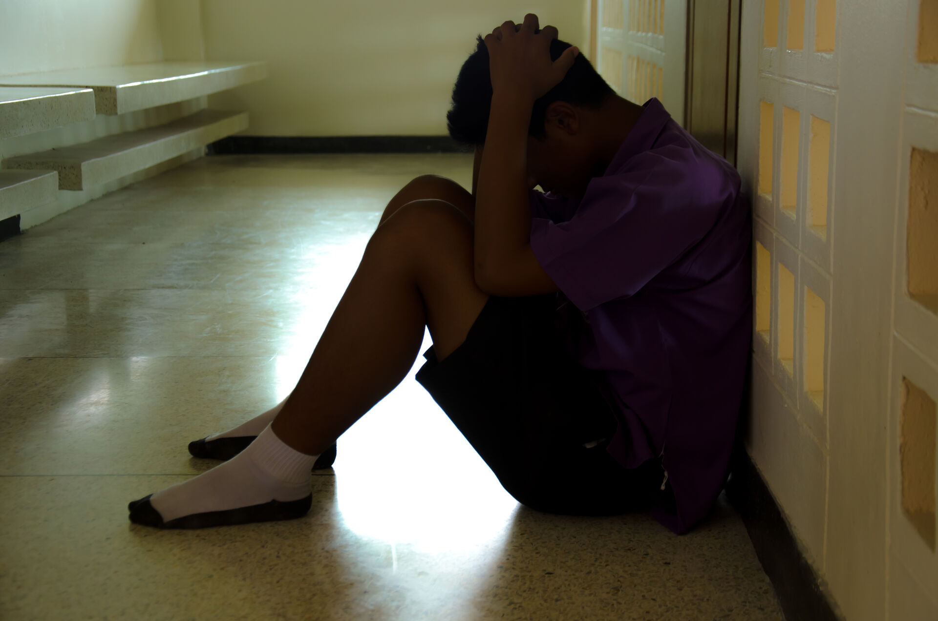 Sad male teenager sitting on the floor