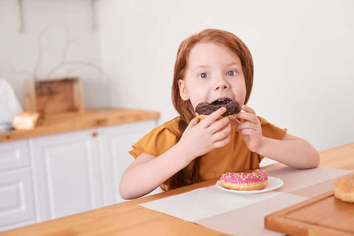 Stock photo of a young girl eating doughnuts