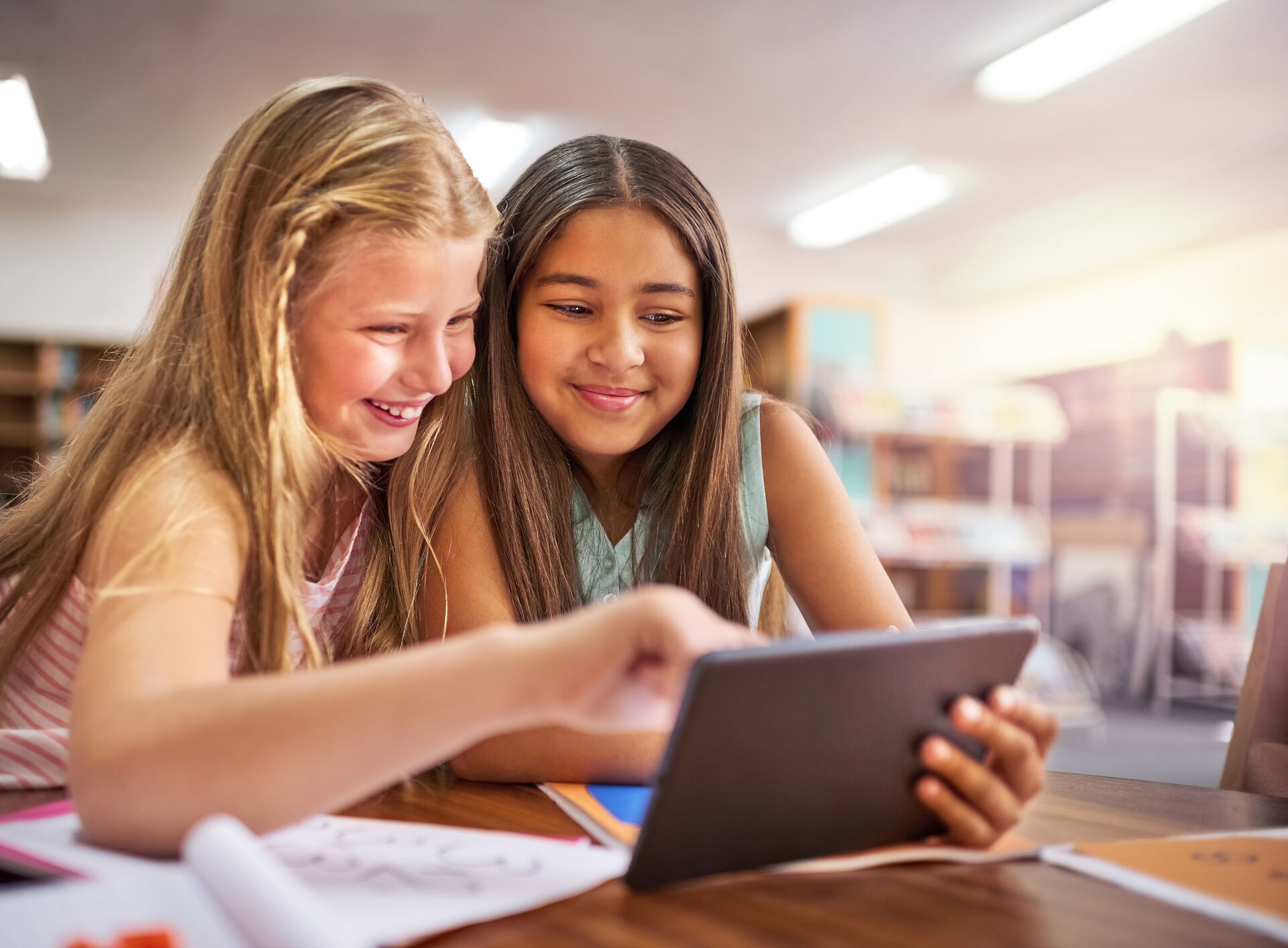Two young students working together, looking at a tablet