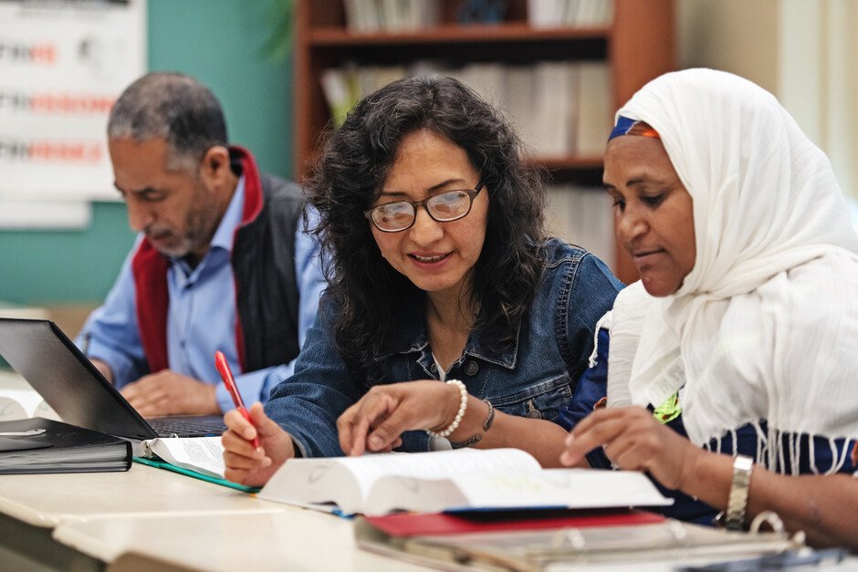 Bildet viser tre vaksne menneske som arbider saman i eit klasserom