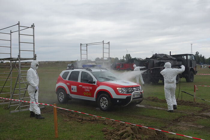 Men in prtective clothes cleaning a car as part of an emergency preparedness exercise