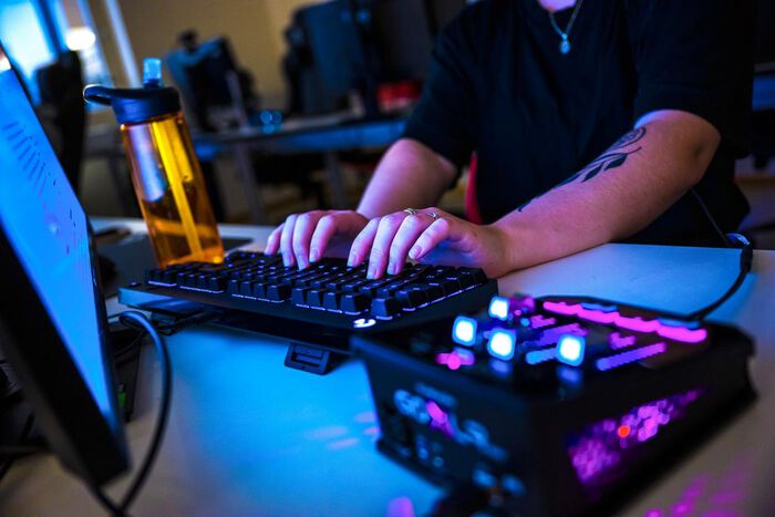 The picture shows someone sitting in front of a PC, gaming