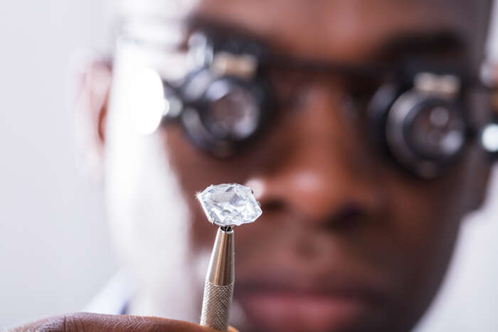 Photograph of a person examining a diamond with a magnifying glass