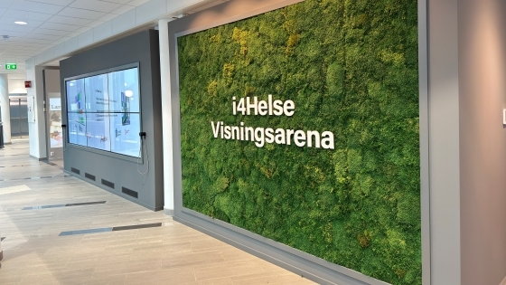 ein stor skjerm på en vegg med digitalt innold til venstre og ein grønn mosevegg med teksten i4helse visningsarena