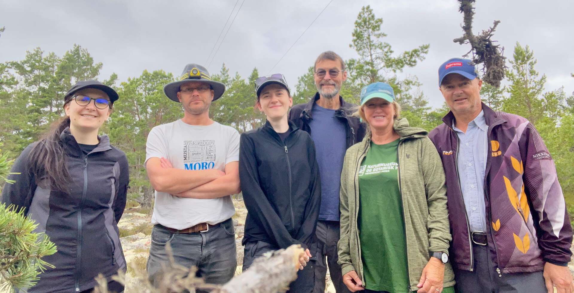 Seks menneske oppstilte til bilde i skogen