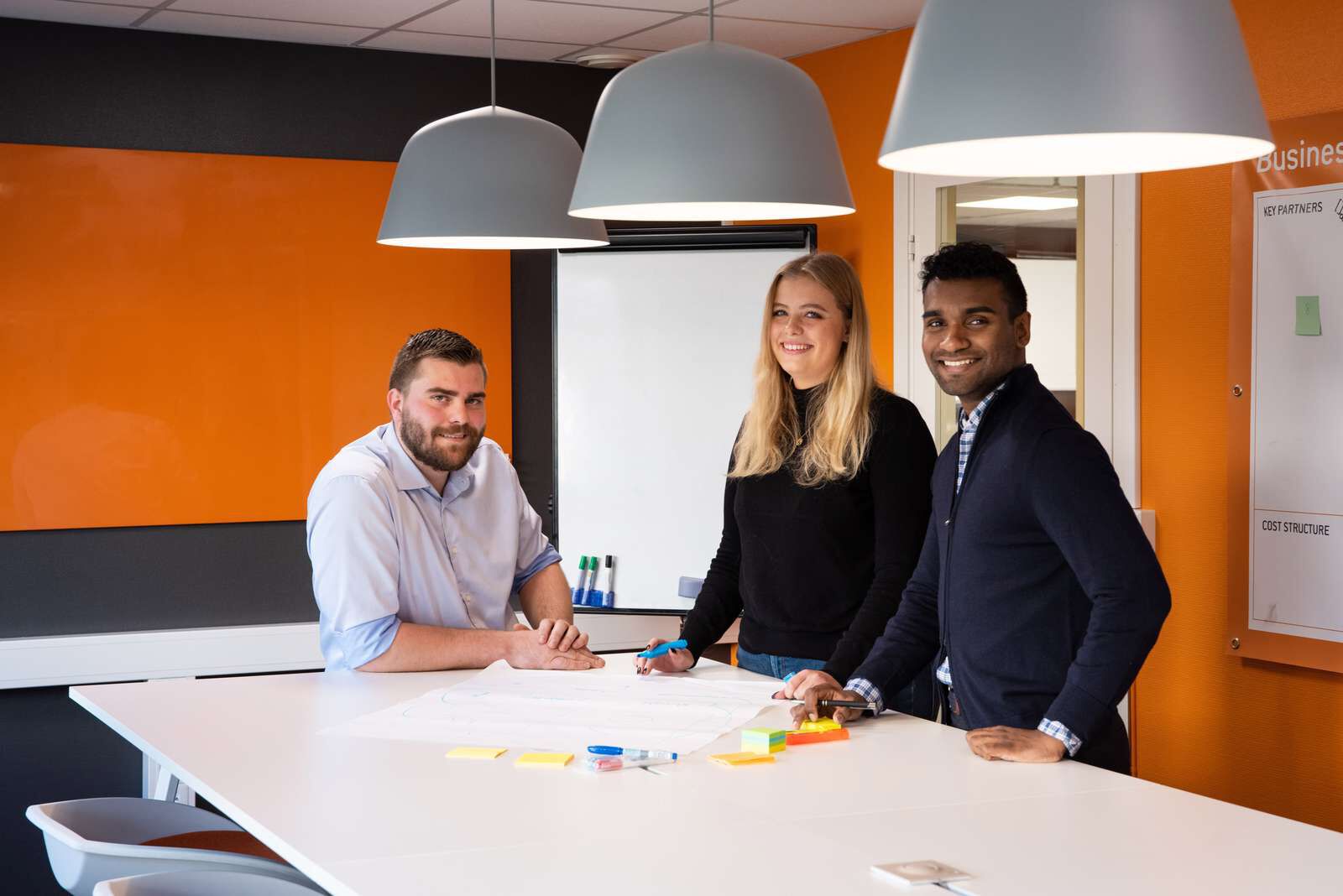 Tre studenter rundt et bord som jobber med noe sammen