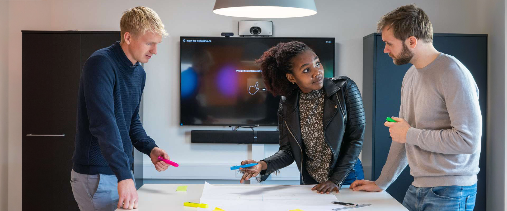 Three students working on a strategy, markers, paper
