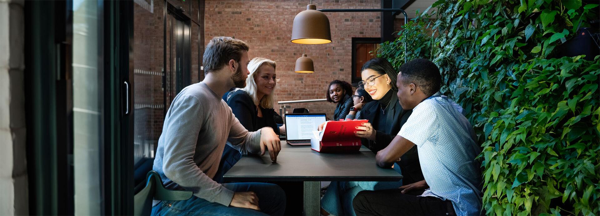 A group of four students working, reading the book of Norwegian laws
