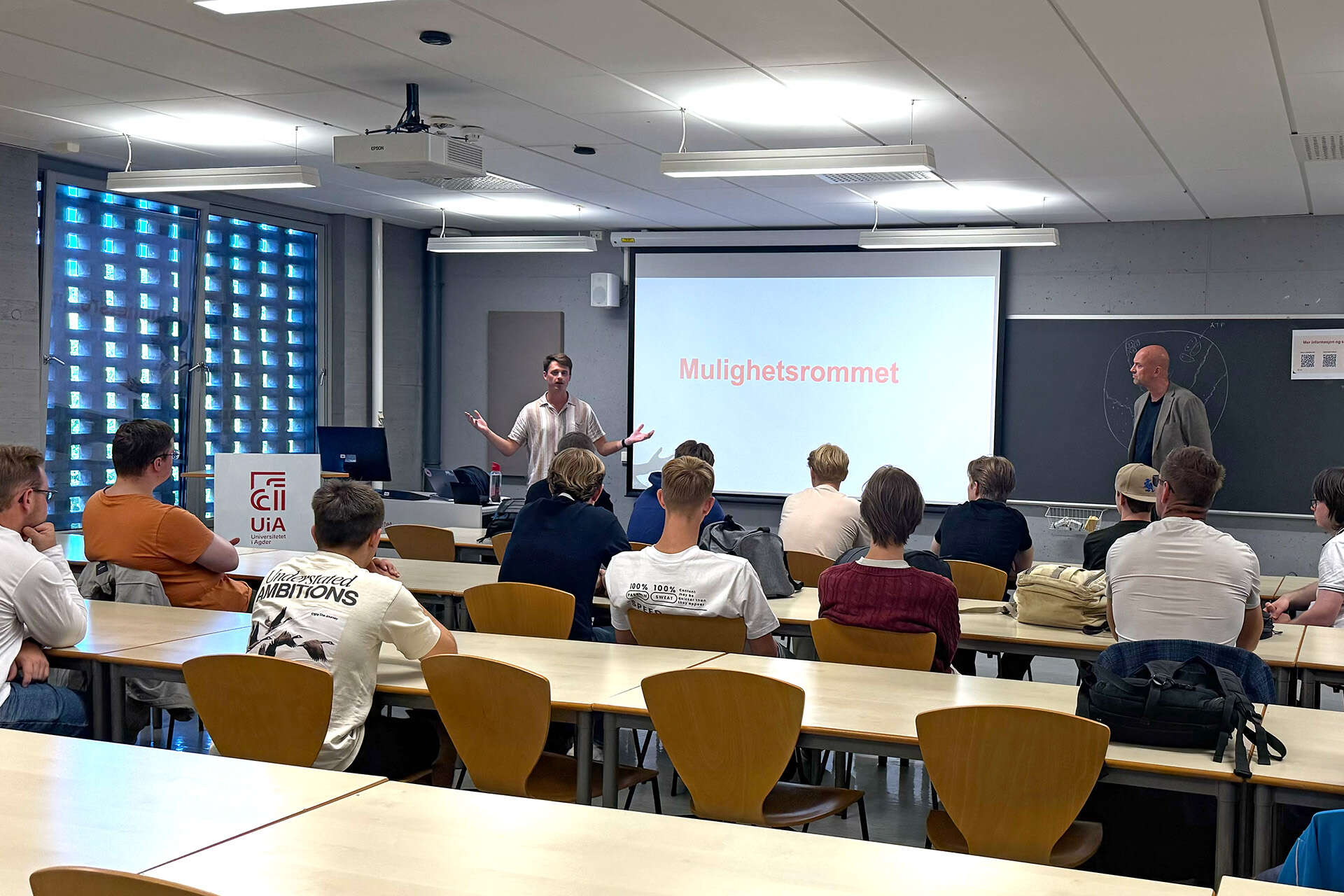 Vegard Sletten Ek og dekan Anders Johan Wickstrøm Andersen presenterte Menn i sykepleie UiA for studentene på pizzatreffet på Campus Kristiansand.