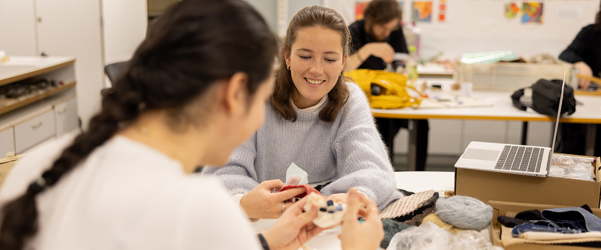 Studenter i tekstilverksted lager kunst av tekstil og garn