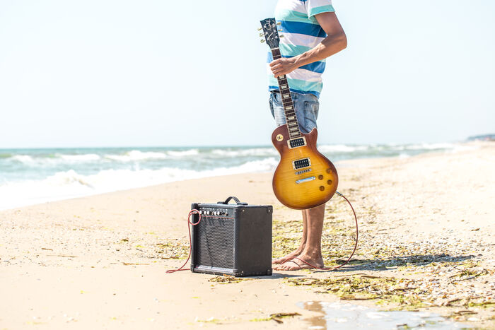 Mann som står på strand med gitar