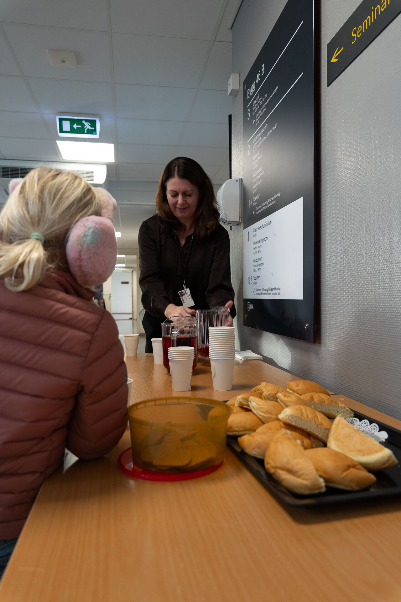 Biletet viser ei voksen som deler ut boller, saft og pepperkaker