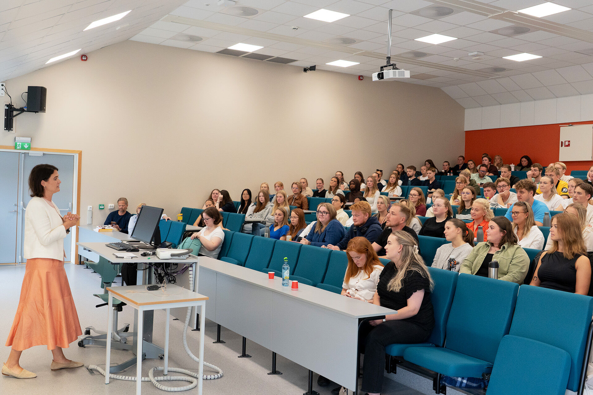 Bildet viser kunnskapsministeren som snakker foran en stor gruppe studenter i undervisningsamfi