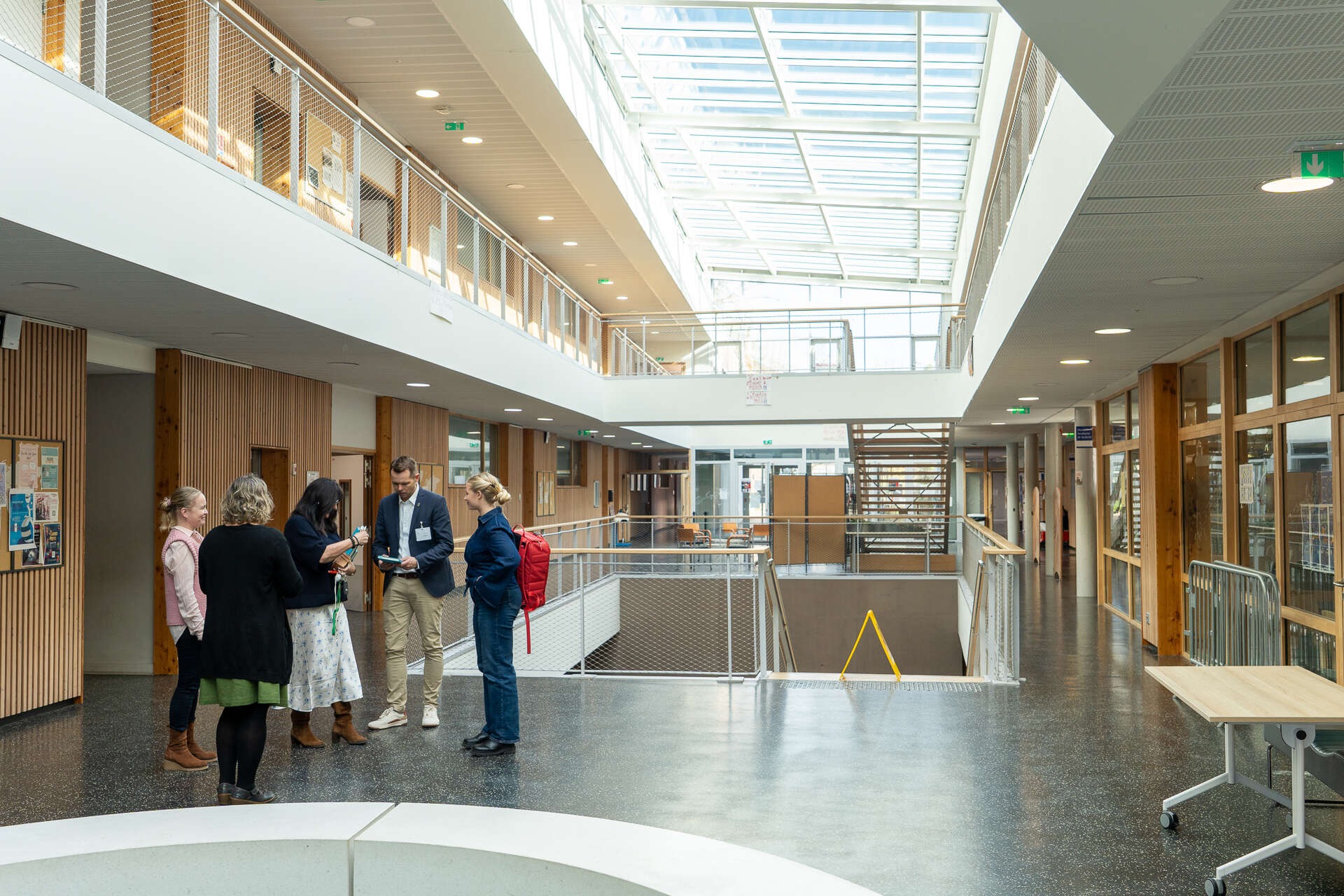 Bildet viser ei gruppe på fem personar i eit lyst og åpent fellesareal med galleri