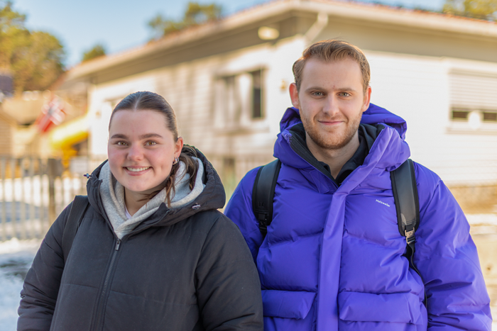 Bildet viser Anniken Bjørnhom og Bendik Aasemoen Solberg, hvit barnehagebygning i bakgrunnen