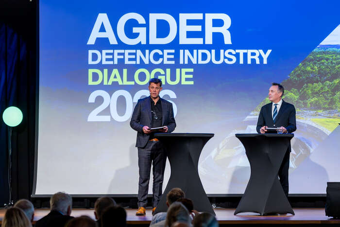 Leif Skiftenes Flak og Tore O. Sandvik på scenen framfor tittelen Agder Defence Industry Dialogue 2026.