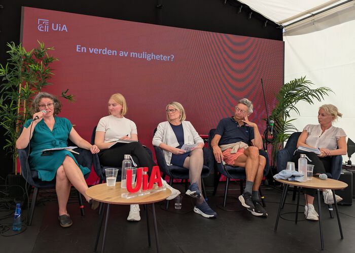 Fem personer sittende i paneldiskusjon.