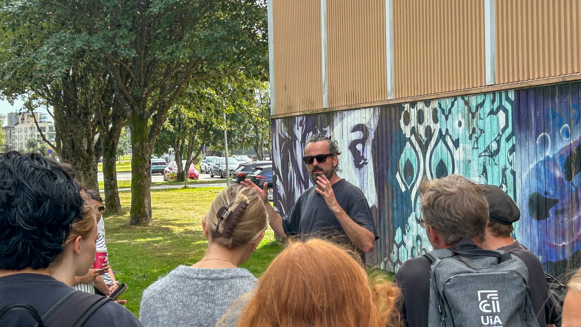 Mann snakker til folkemengde foran grafittivegg