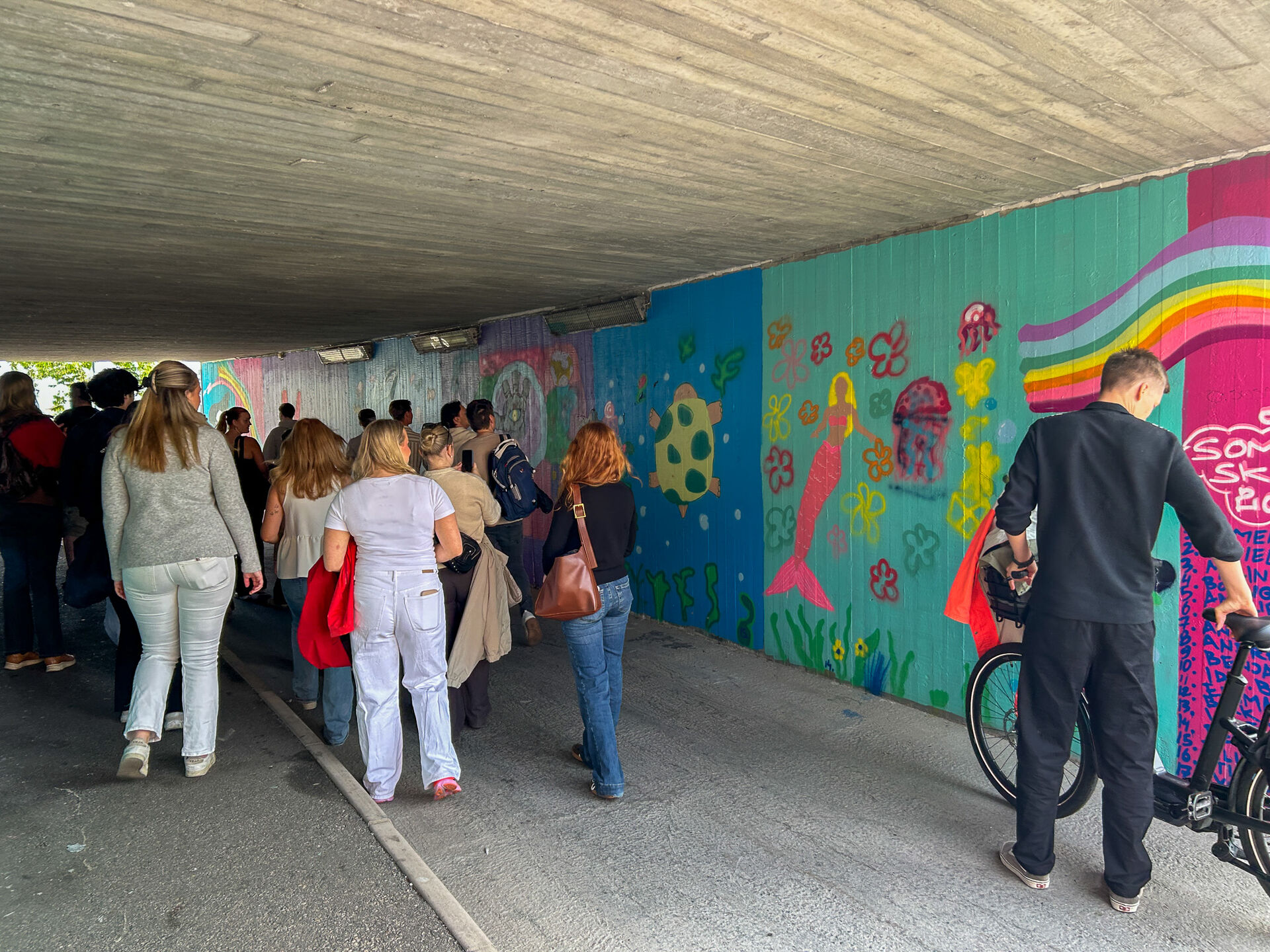 Studenter gående i tunnel med fargerike vegger