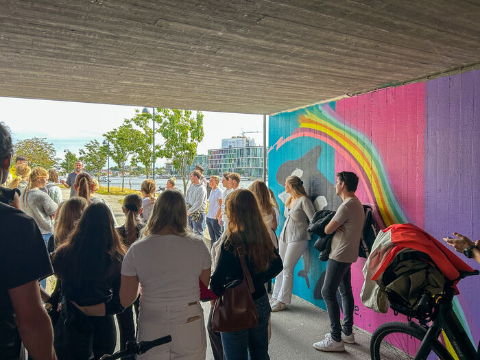 Folkemengde foran fargerike vegger i tunnel.