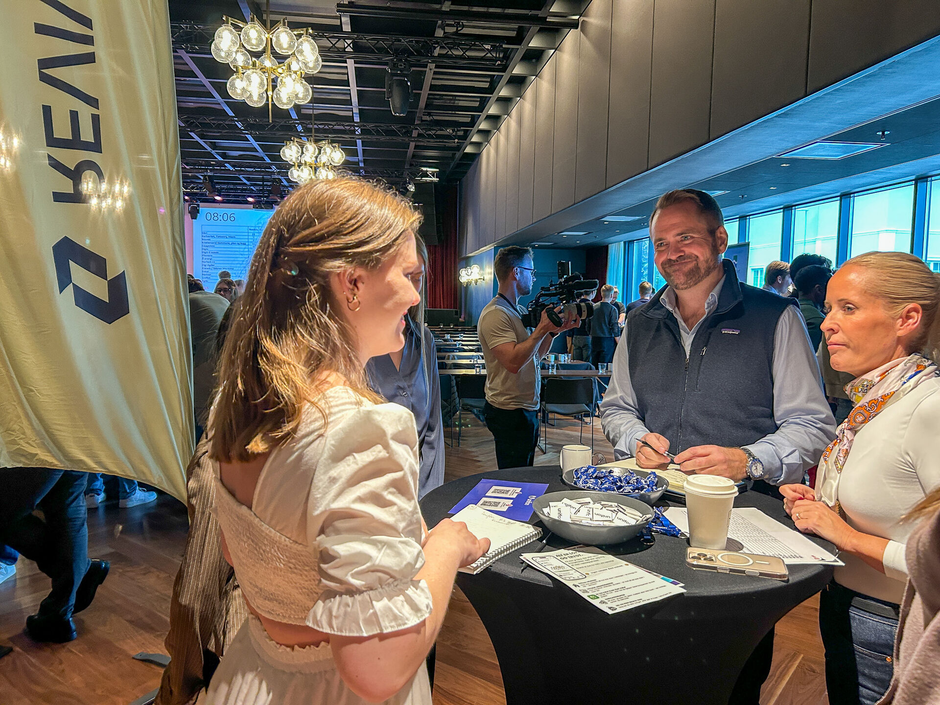 Tre personer som snakker sammen ved stand