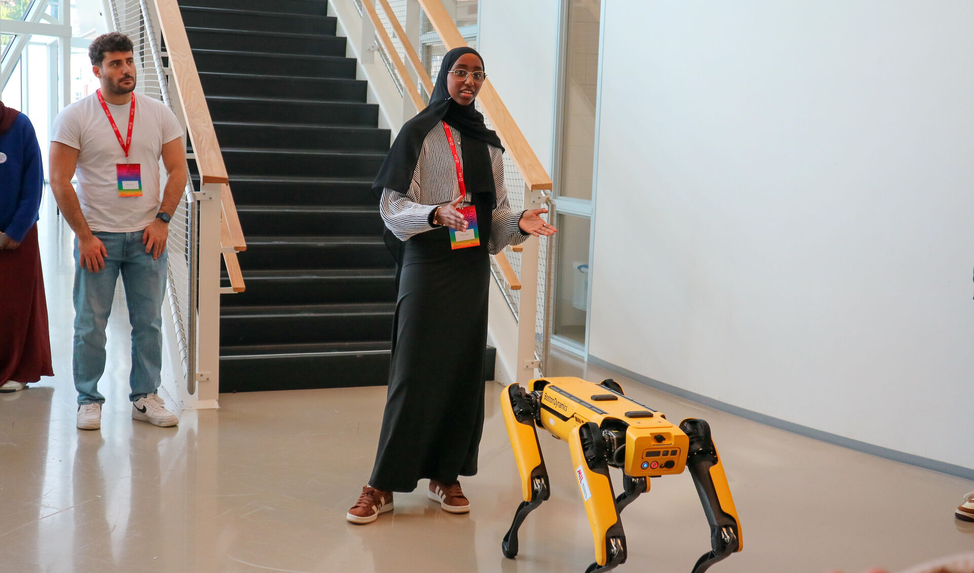 Kvinne som snakker og viser en robot, foran en trapp
