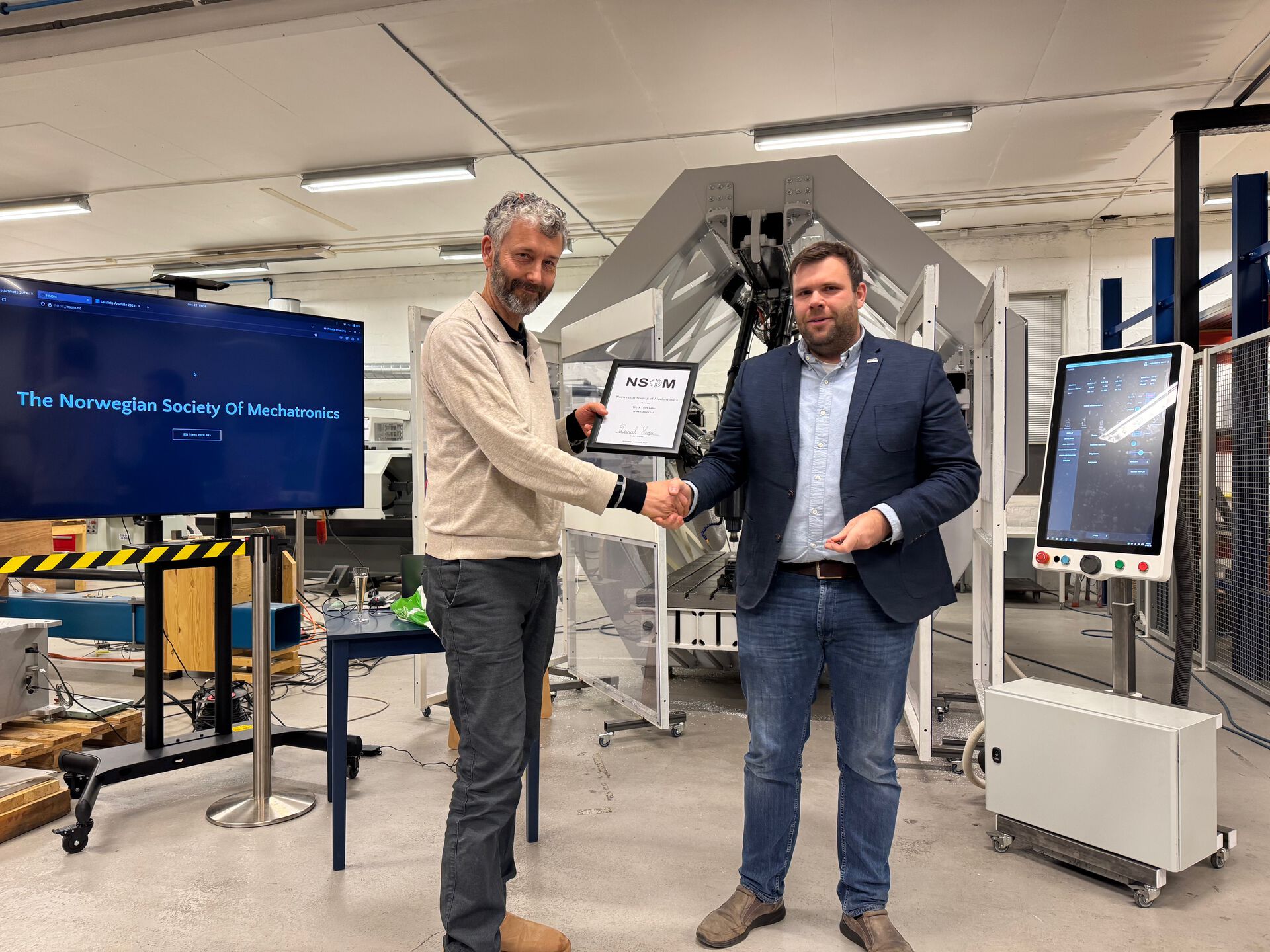 Bilde av Geir og Daniel foran en industrimaskin. 