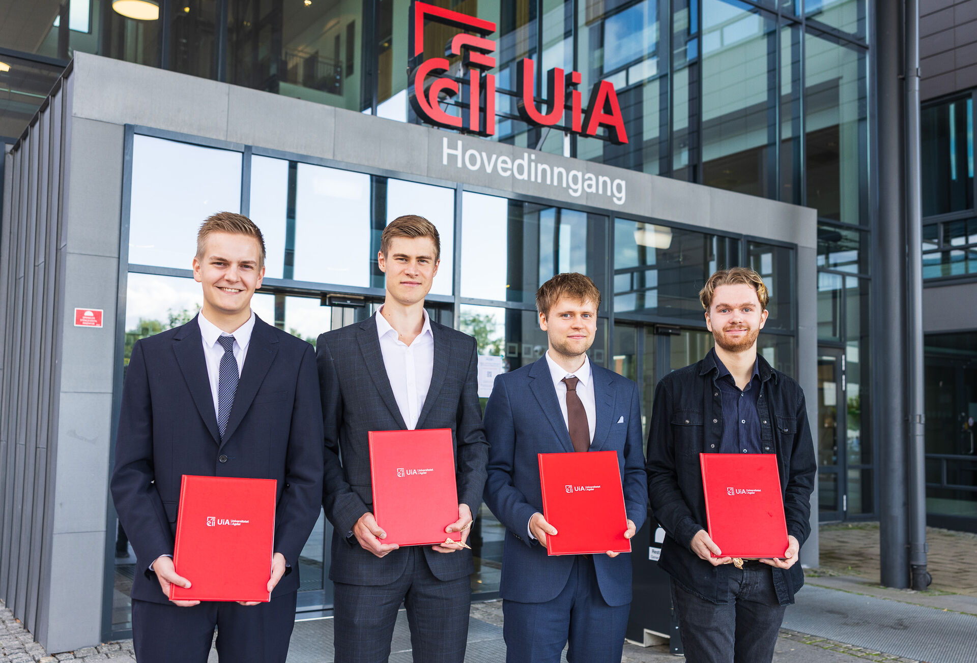Fire gutter står med røde diplomer