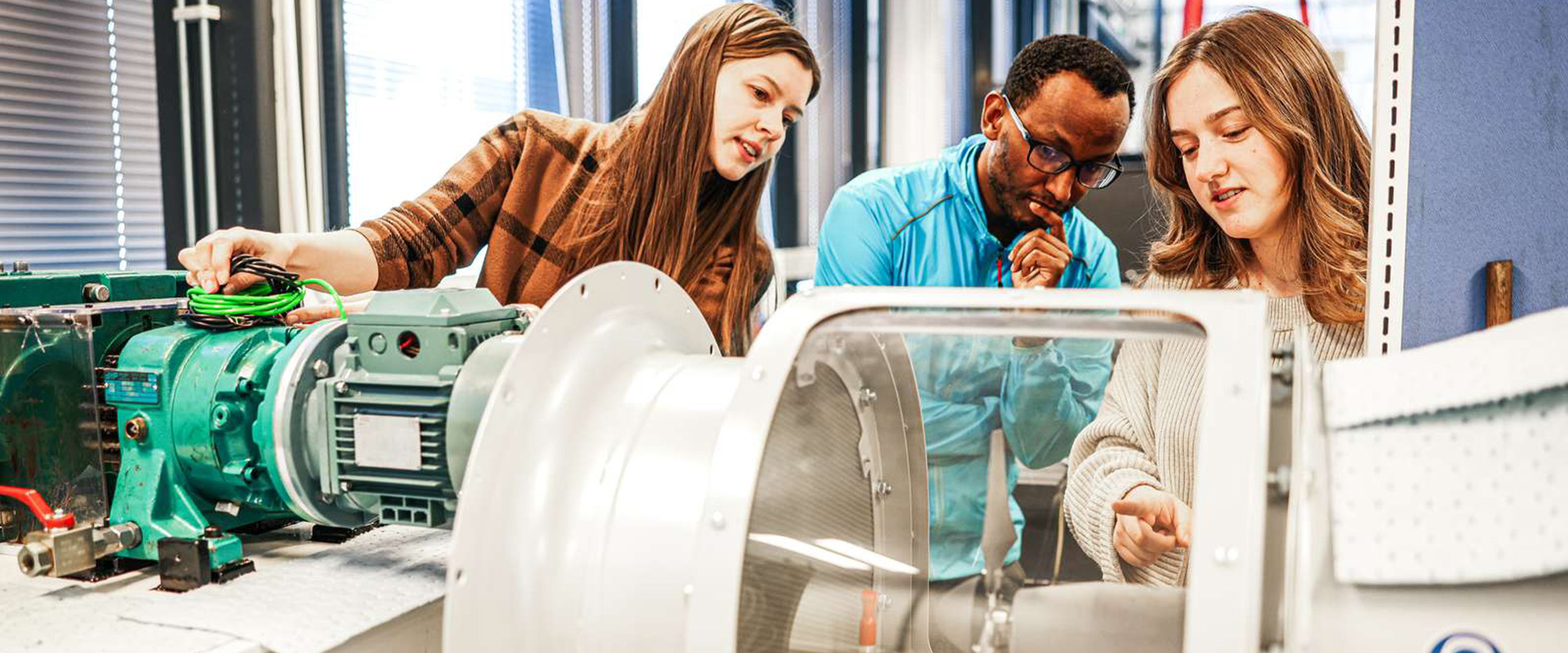 Three individuals are inspecting a propeller in a turbine