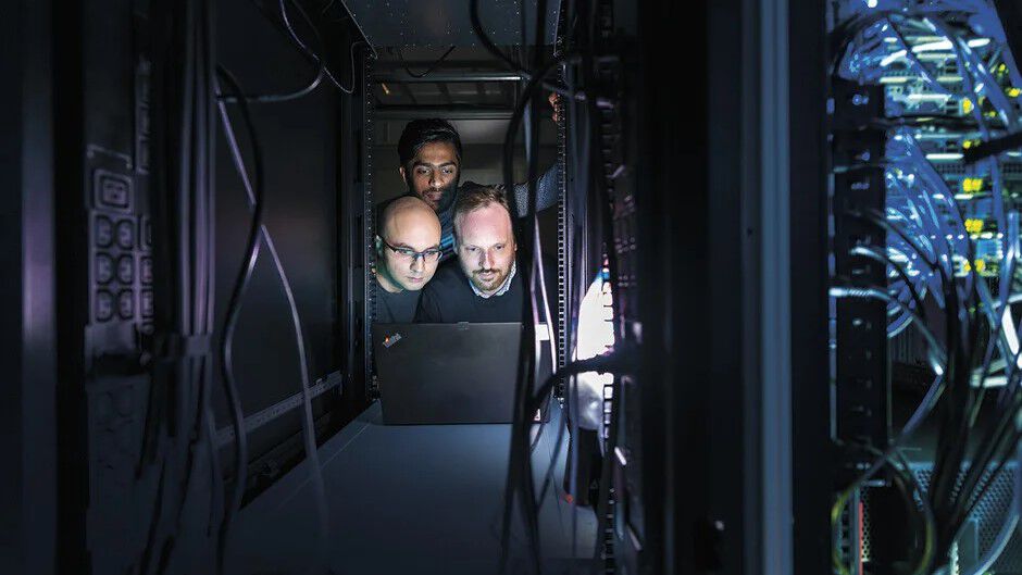 Three people looking at a screen with their faces lit up