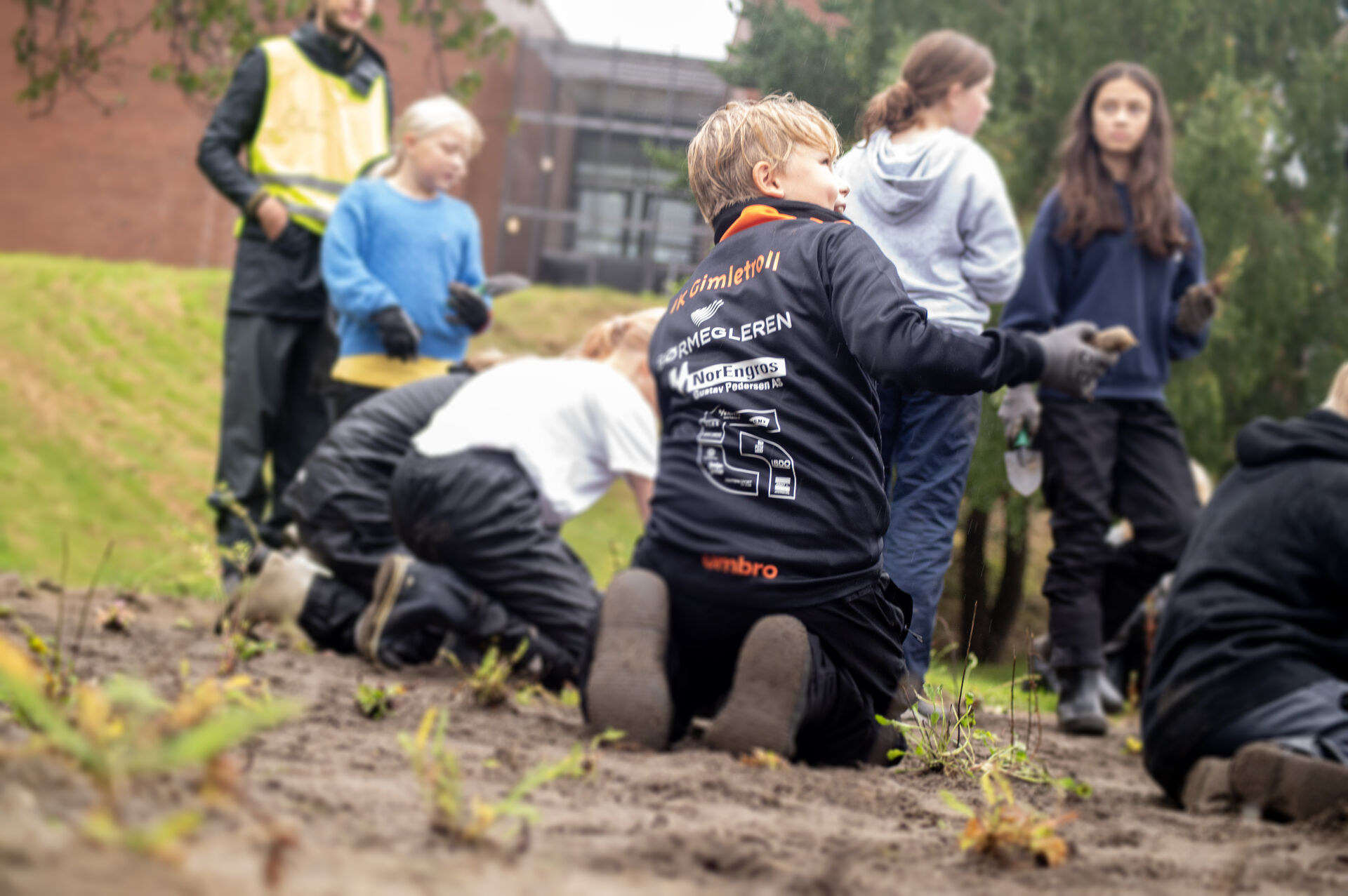 Barn som jobber med å plante i blomsterenga