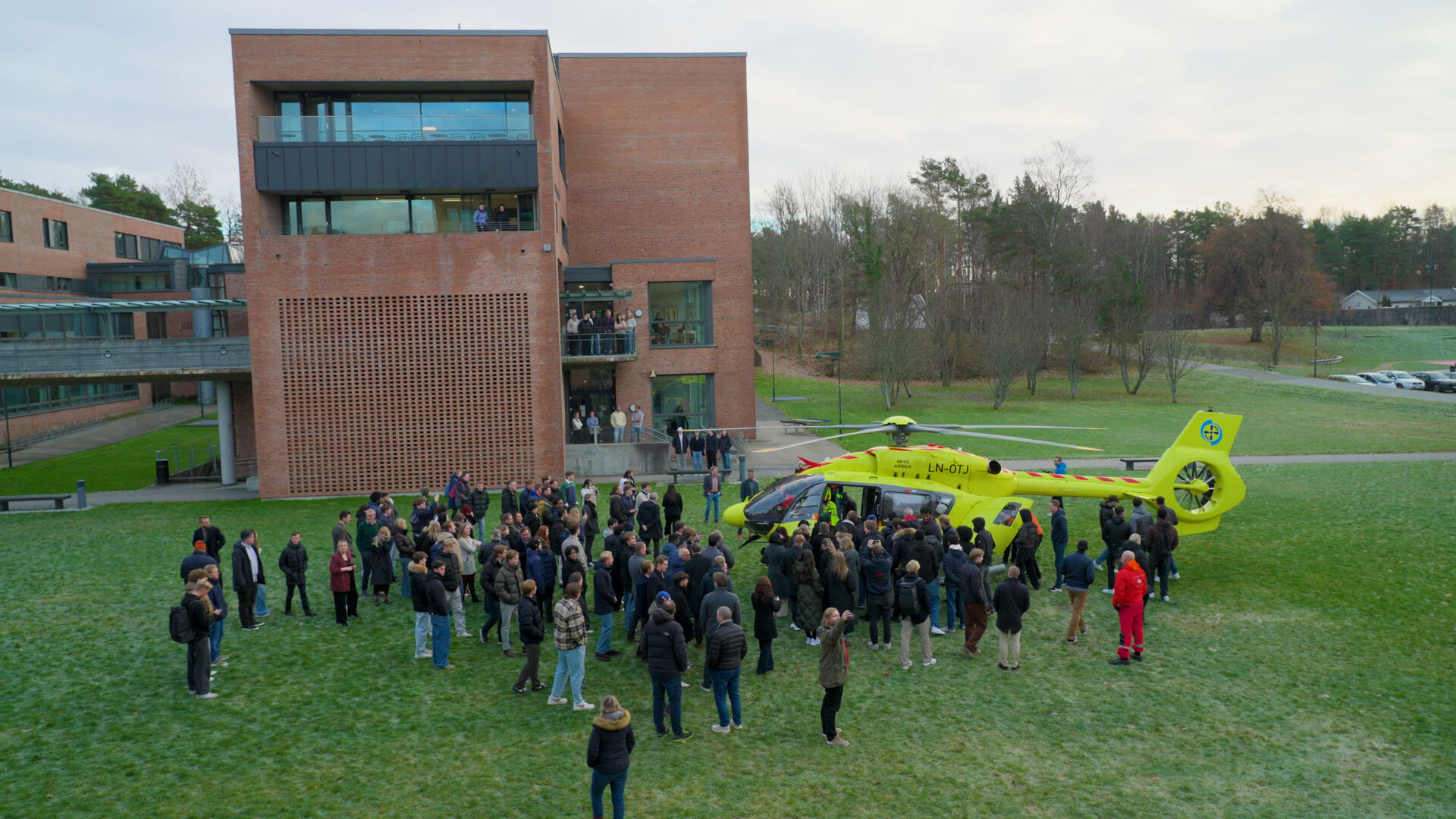 Bildet viser et helikopter med studenter rundt.