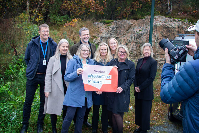 Bildet viser UiA-rektoren som mottar en sjekk, sammen med flere andre involverte