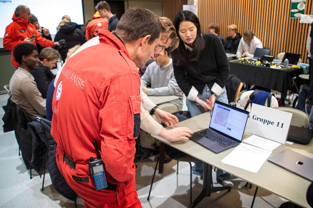 Bildet viser helikopterpilot Trygve Borgen som ser på studentenes prosjekter.